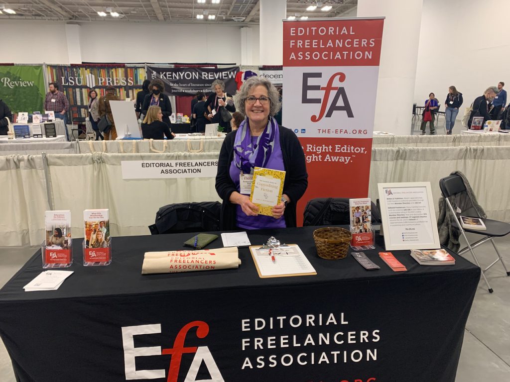 Volunteer behind a table covered with a black EFA logo drape and laid out with brochures and marketing materials